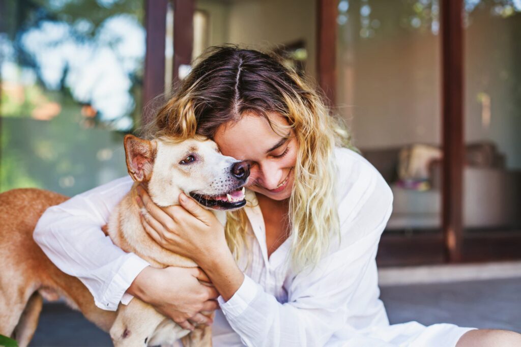 Lady with blonde hair hugging her older dog. Spay - neuter procedures can help animals stay healthy longer.